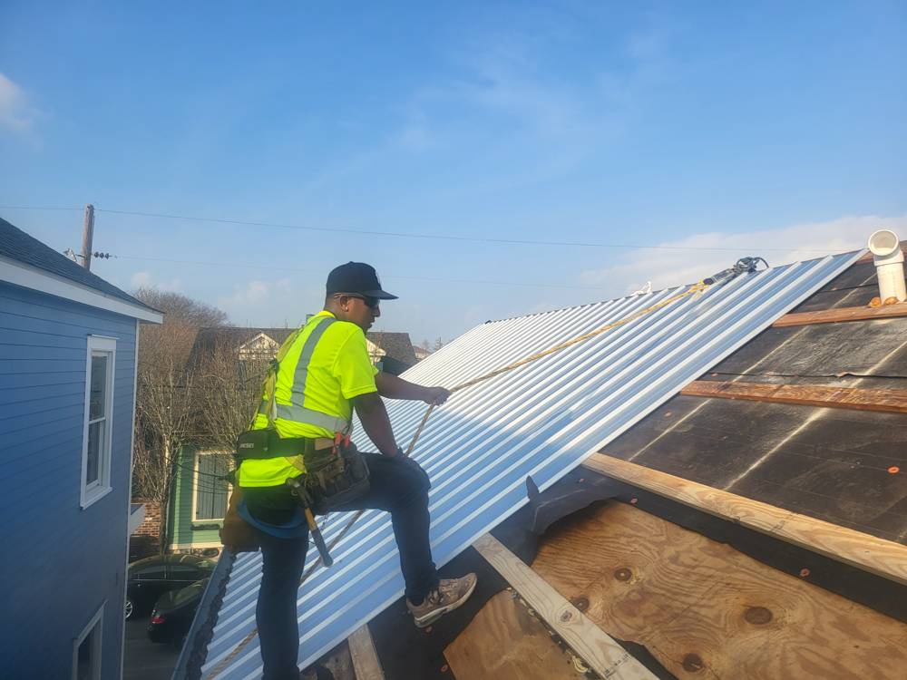 Crew member installing standing seam metal roof panels