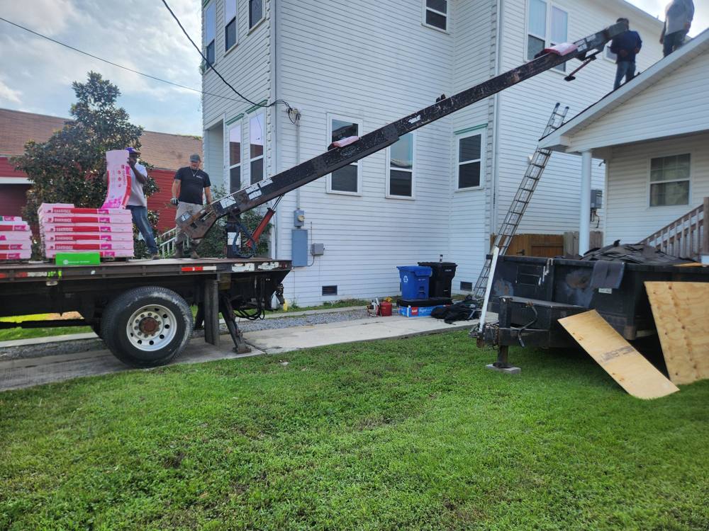 Conveyor truck loading shingles onto a two-story house