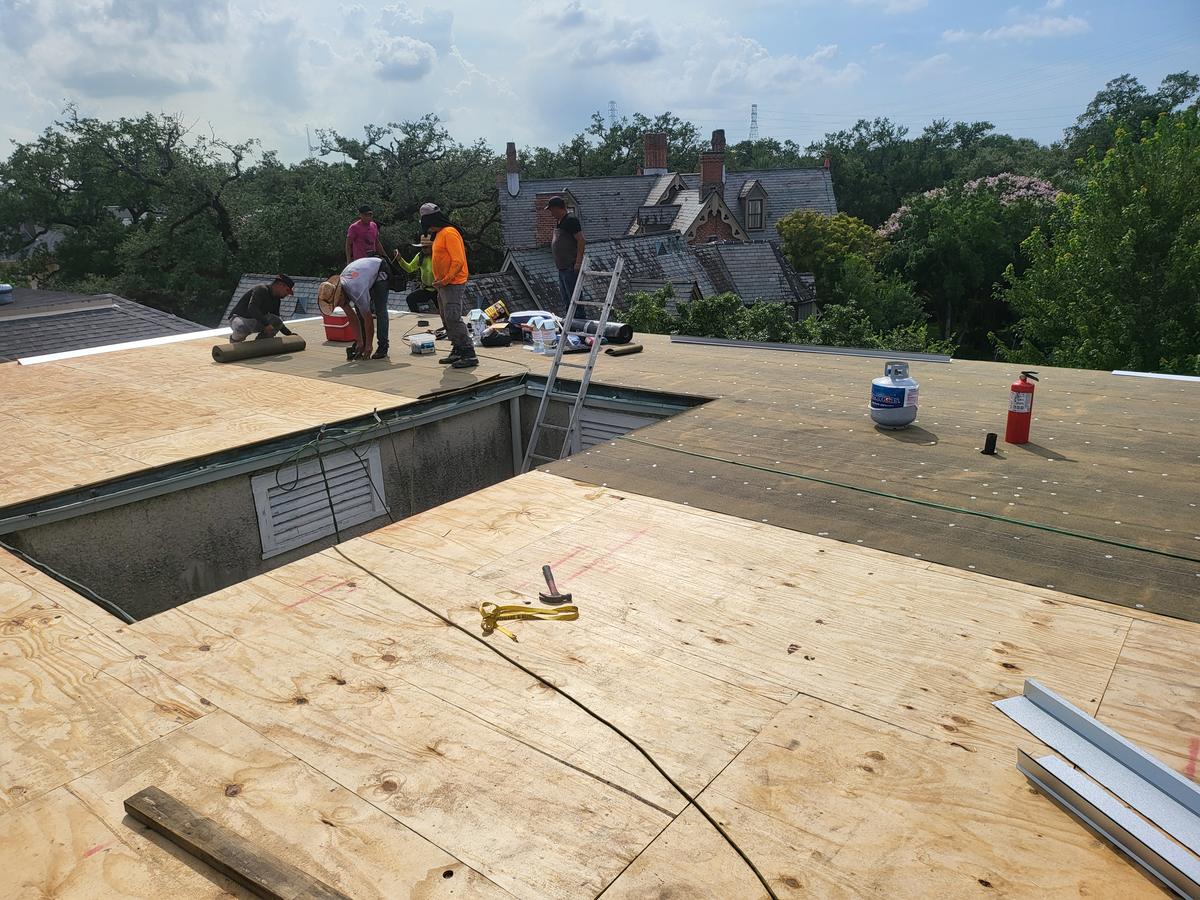 Crew installing new decking and base sheet on a flat roof