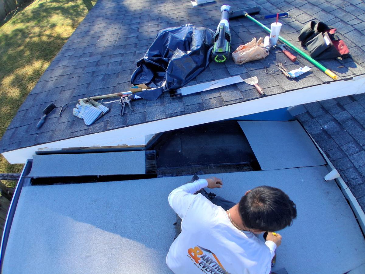 Roofer repairing a damaged low-slope section next to a shingle roof